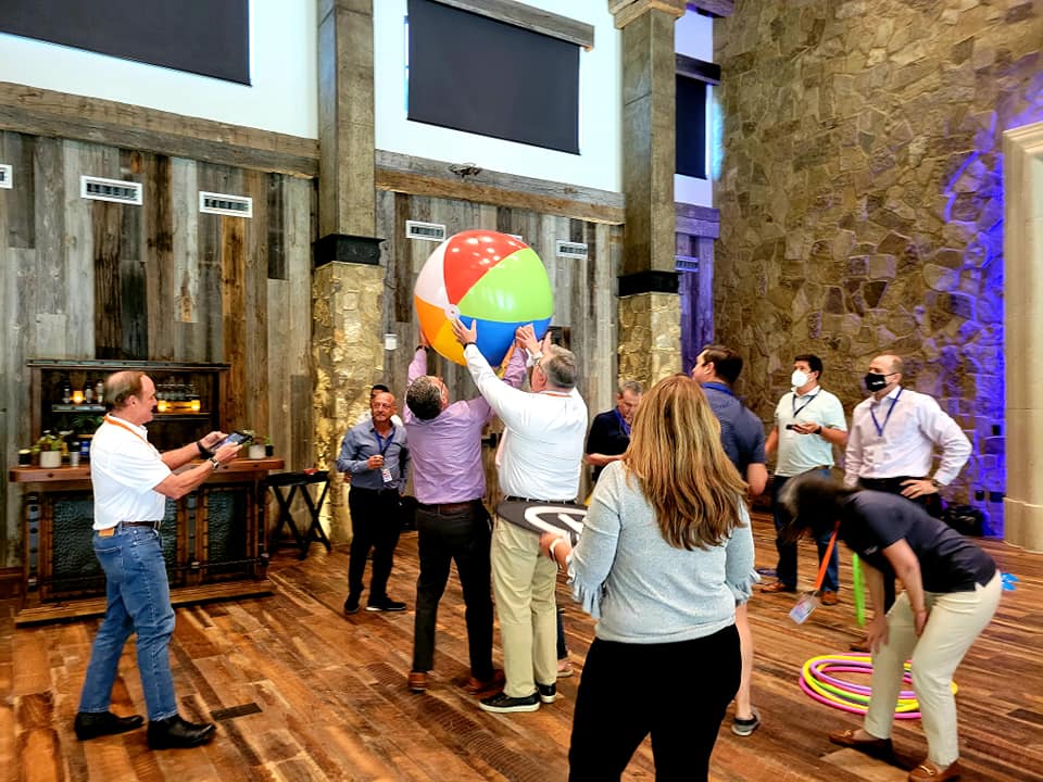 Team members collaborate to maneuver a large beach ball during the Game of Drones team building event, combining coordination and communication in a fun and dynamic environment.