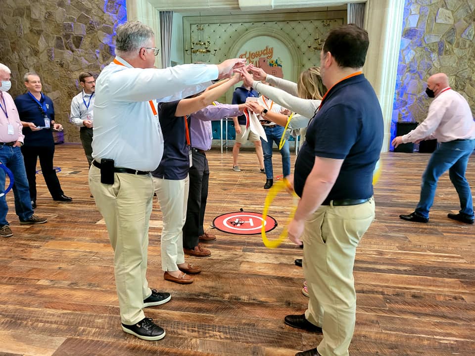 Participants work together to guide a drone through obstacles using teamwork and strategy during the Game of Drones team building event, fostering collaboration and problem-solving.