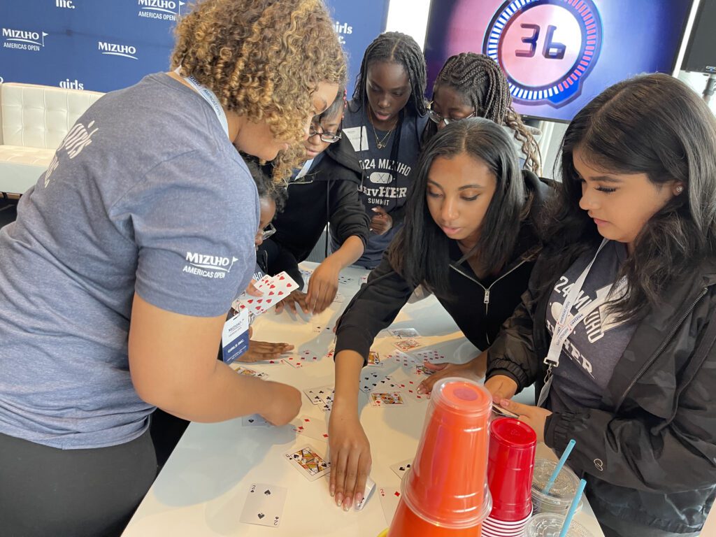 Participants focused on a card stacking challenge during In It to Win It, displaying teamwork, concentration, and quick thinking as they work together to complete the task within the 60-second time limit.