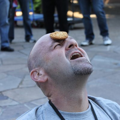 Participant attempting the 'Cookie Face' challenge in the In It To Win It team building event. The fast-paced competition promotes laughter, teamwork, and friendly rivalry as teams compete in fun 60-second games.