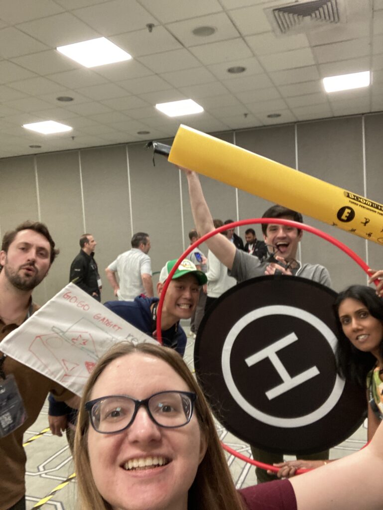 Team members pose with drone navigation tools and equipment after completing a successful round of the Game of Drones team building challenge.