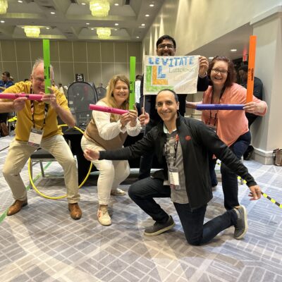 Team enthusiastically posing with colorful drone controllers during a high-energy Game of Drones team building event.