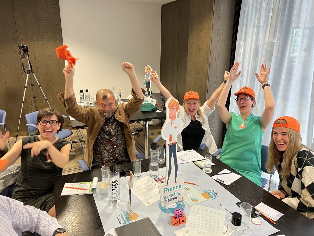 Team members celebrating and enjoying the Leadership Stories team building event, showcasing leadership skills in an engaging, board game-style competition.