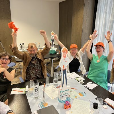 Team members celebrating and enjoying the Leadership Stories team building event, showcasing leadership skills in an engaging, board game-style competition.