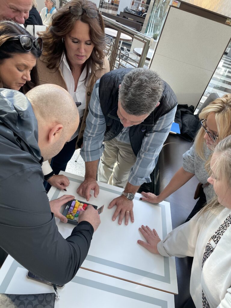 A team collaborating during a puzzle challenge at a team building event, gathered around a table focused on solving a task.