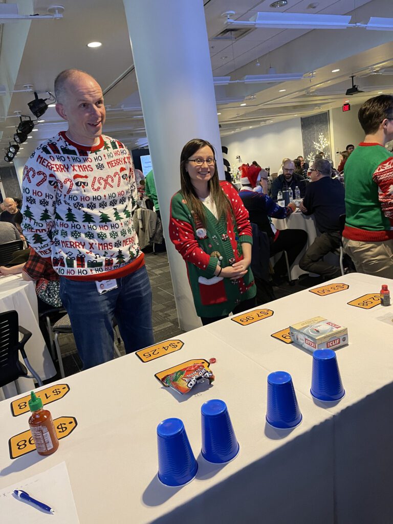 Participants in festive sweaters ready to play at a holiday-themed foodbank showdown team building event.