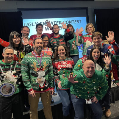 Team members showcase their holiday spirit in festive sweaters during a fun-filled team building holiday party.