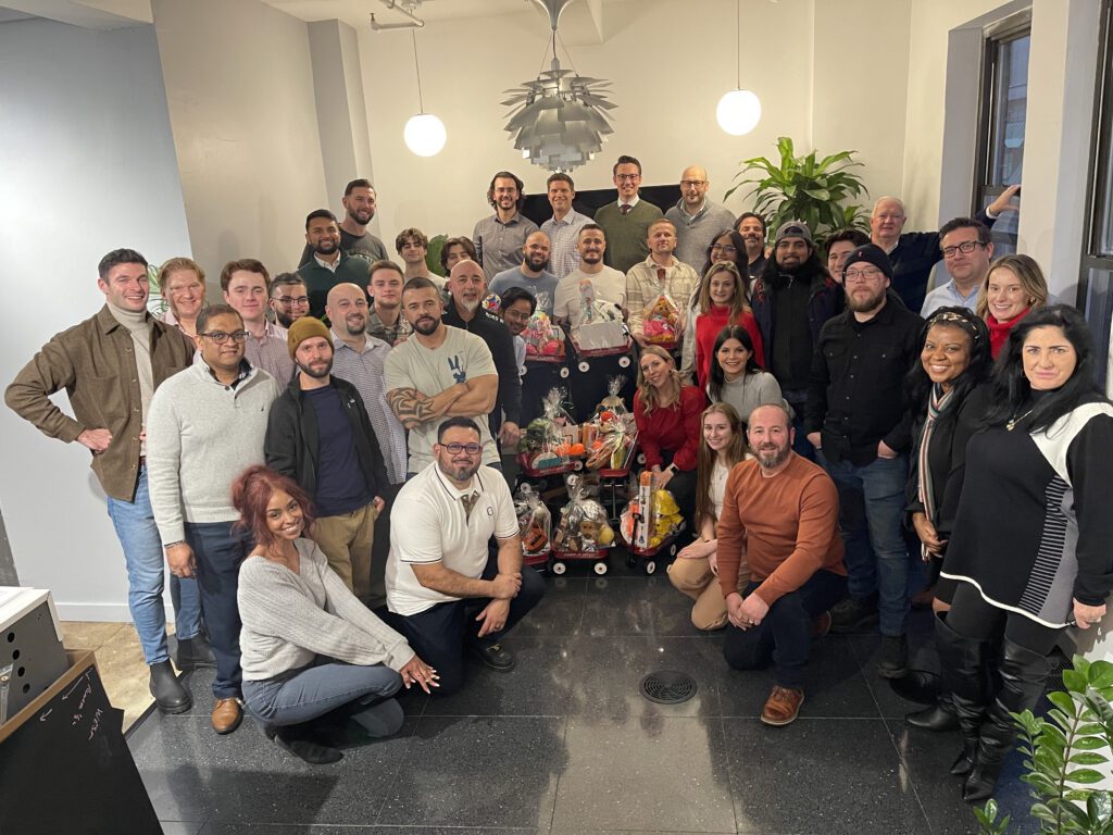 Team posing with holiday gift baskets, celebrating together during a festive team building event.