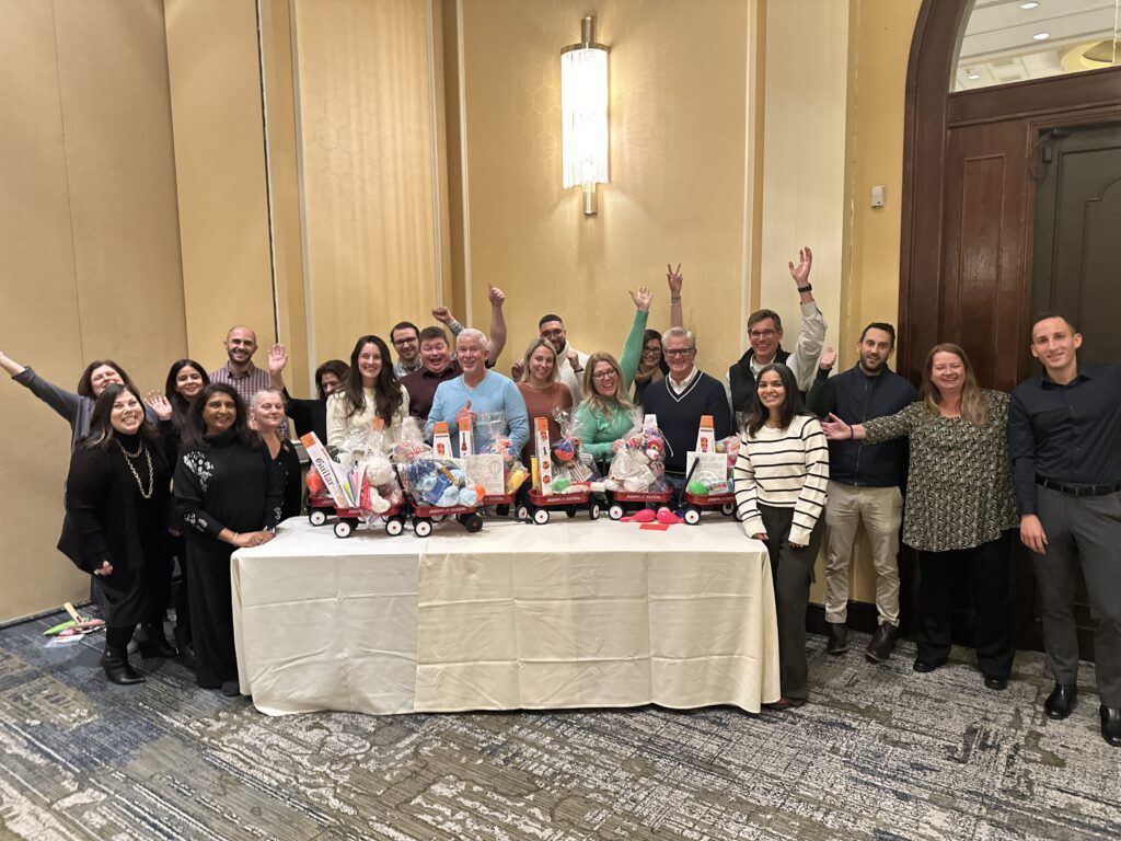 Team celebrating after completing holiday wagons filled with gifts for donation during a festive team building event.