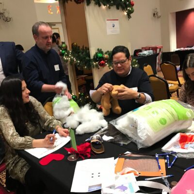 Team members collaborate to stuff teddy bears during a holiday team building activity focused on creativity and giving back.