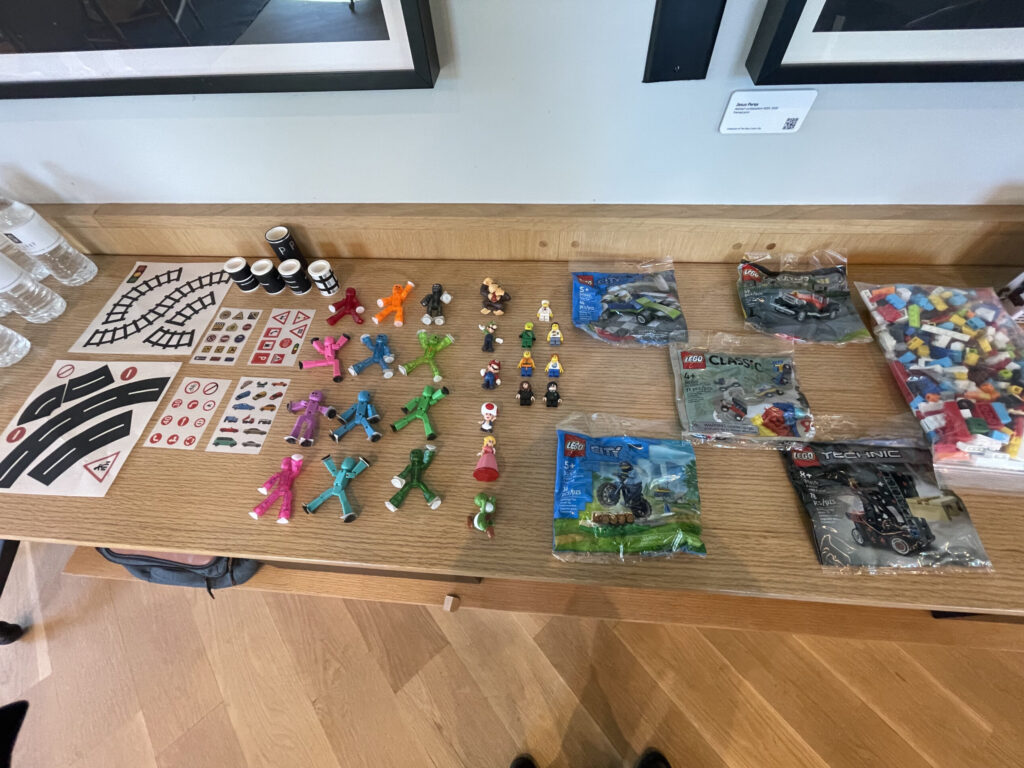 Table setup with small brick building kits, figures, and props ready for a stop motion animation team building activity, encouraging creativity and teamwork.