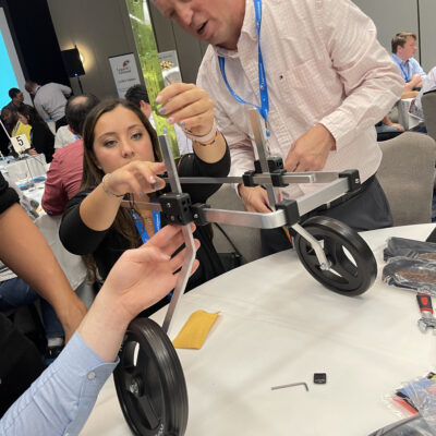 Two participants assemble a pet wheelchair by adjusting its frame and securing parts. Their concentration reflects the collaborative effort required to ensure the device is functional, highlighting teamwork and problem-solving in this meaningful activity.