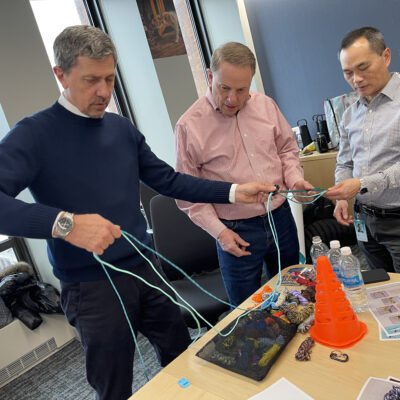 Three participants work together to tie ropes during the Mission ImPAWssible team building activity.