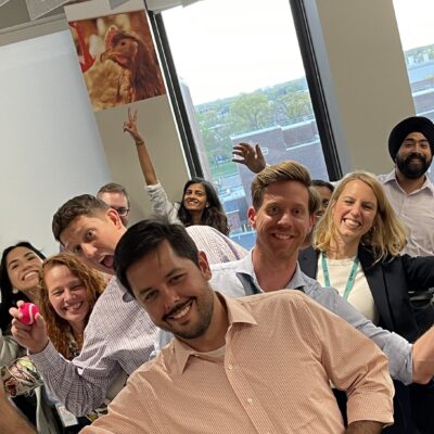 A group of colleagues smiling and holding colorful objects, clearly enjoying a fun and energetic moment during a team building event.