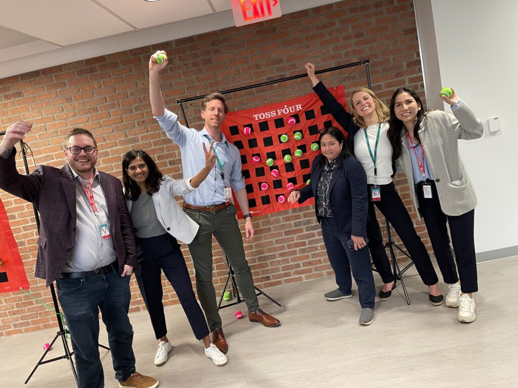 A group of participants happily posing with toss balls, showing enthusiasm and teamwork during a fun activity at a team building event.