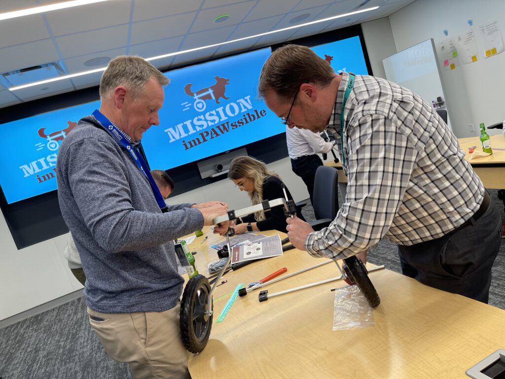 Two participants working together to assemble a pet wheelchair during the 