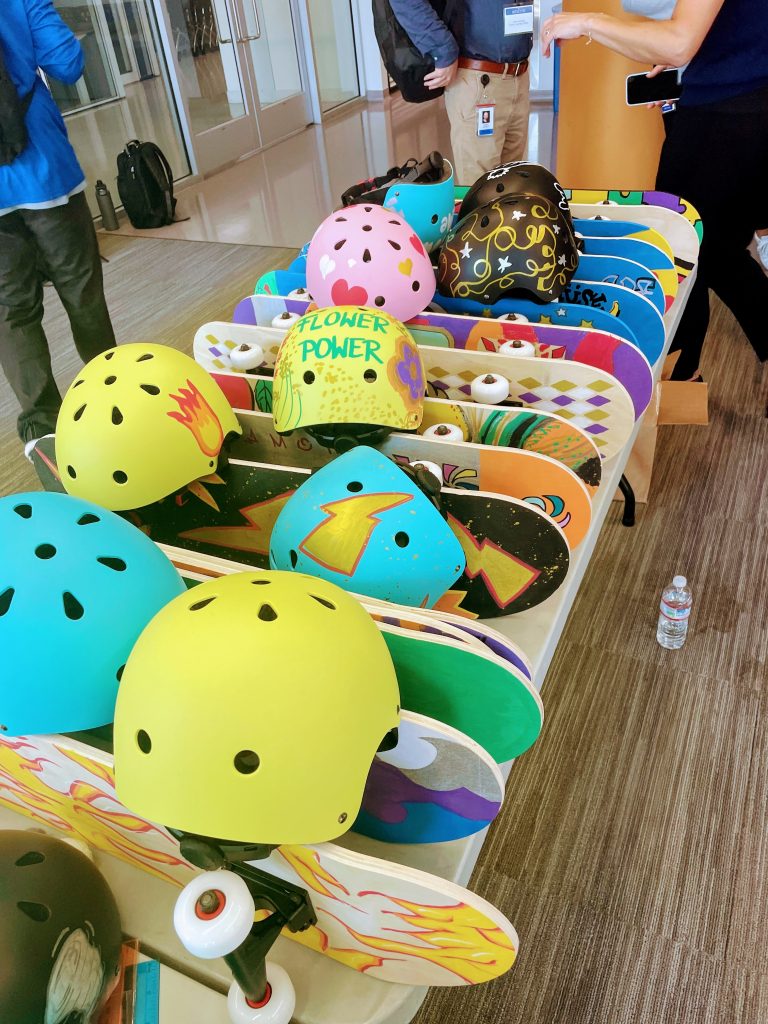 Colorful skateboards and helmets decorated for a charitable team building event. Participants design and assemble skateboards to be donated to children's charities, promoting creativity, teamwork, and community impact.