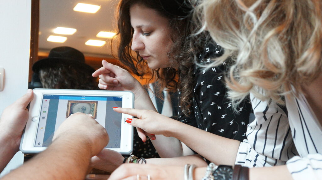 Participants closely examining clues on a tablet during the Sleuth: The Murder Mystery Scavenger Hunt team building event.