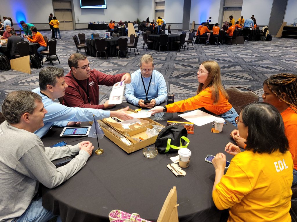 Team members collaborate around a table, assembling a guitar at the Charity Guitar Build event, blending creativity with a mission to give back to the community.