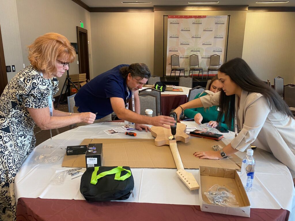 Team members collaborate to build an electric guitar during the Charity Guitar Build team building event.