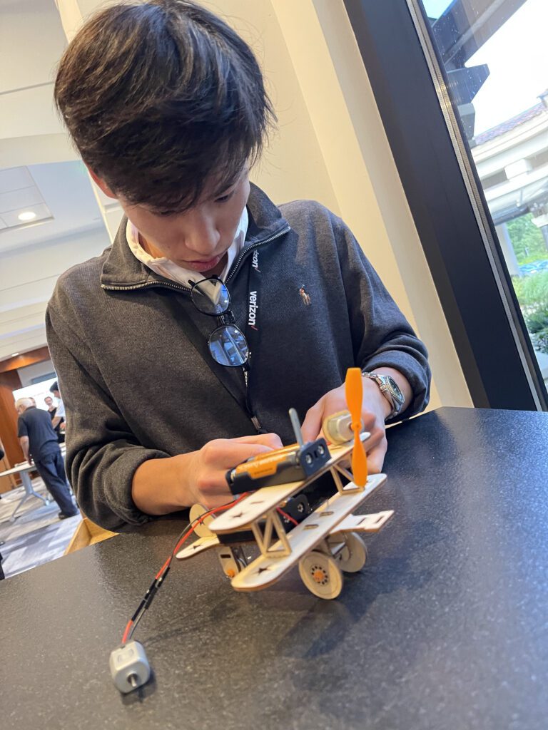 A participant carefully assembling a miniature model airplane with a propeller during the STEM Speedway team building activity, focusing on attention to detail, creativity, and hands-on engineering skills.