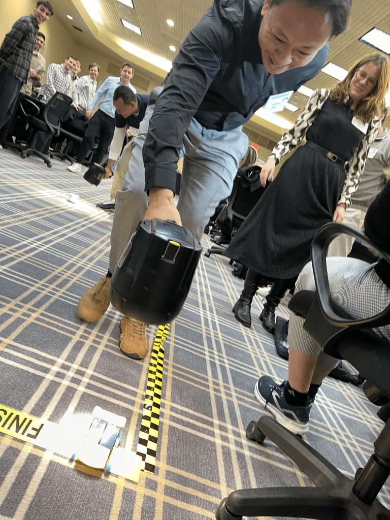 A participant watches intently as their STEM-built car crosses the finish line during the STEM Speedway race at a team building event.