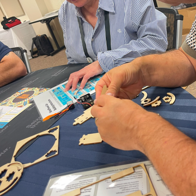 Participants assembling wooden parts of a STEM project kit during the STEM Speedway team building activity, focusing on teamwork, attention to detail, and hands-on construction.