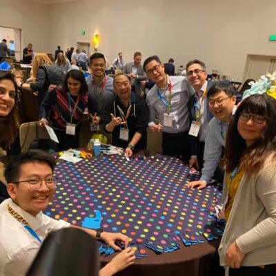 A group of colleagues enjoys the team building experience at the Hope for the Holidays event, working together to assemble colorful blankets for donation to local seniors during the holiday season.