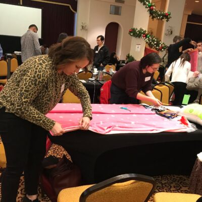 Participants at the Hope for the Holidays team building event work together to craft personalized blankets, spreading warmth and cheer to local seniors during the festive season.