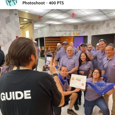 Team Blue celebrating their success during a museum scavenger hunt. A guide captures their victory photo as they proudly display their challenge completion, highlighting teamwork, problem-solving, and fun competition.