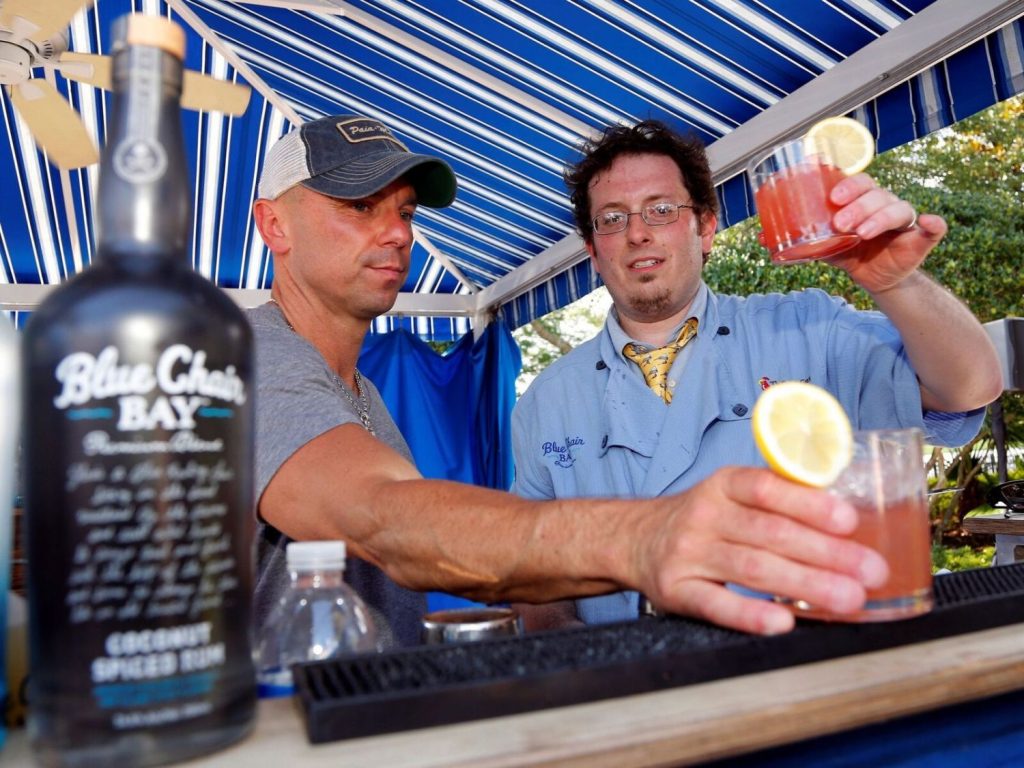 Two team members toasting with freshly made cocktails at a mixology event. The hands-on class promotes teamwork and creativity as participants craft and enjoy their own drinks together.